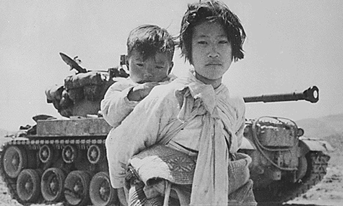 1951년 6월 9일 촬영된 이 사진은 고양시 인근 행주에서 M-26 탱크 옆을 지나는, 아이를 업고 걸어가는 한 어린 소녀의 모습이다. [사진 = 연합뉴스]