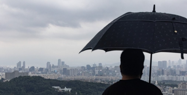 8일 서울 남산 전망대에서 한 시민이 우산을 쓰고 서울 용산과 강남 일대를 바라보고 있다. [출처=연합뉴스]